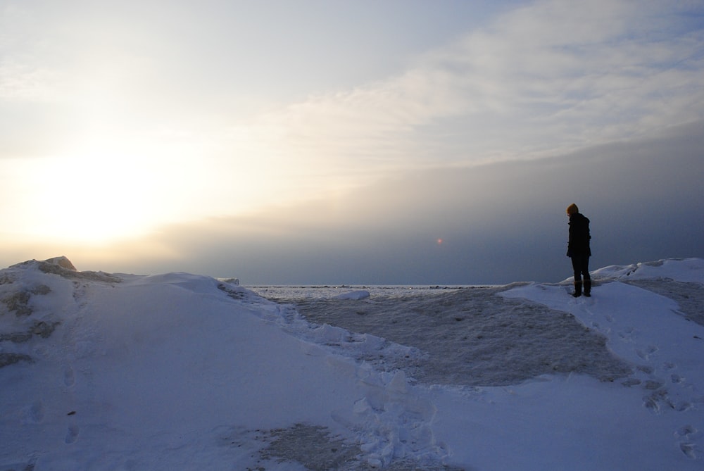 Persona de pie en la montaña nevada bajo la puesta del sol