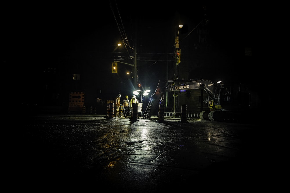 Drei Personen, die in der Nähe eines Versorgungspostens mit eingeschalteten Lichtern während der Nacht stehen