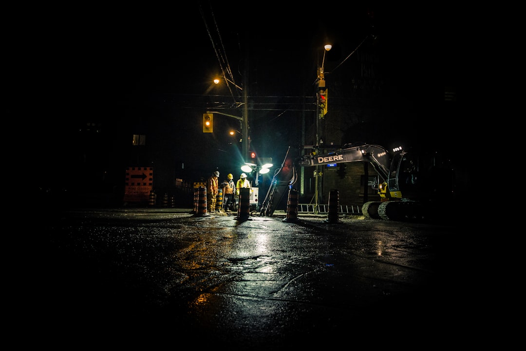 three people standing near utility post with lights turned on during nighttime