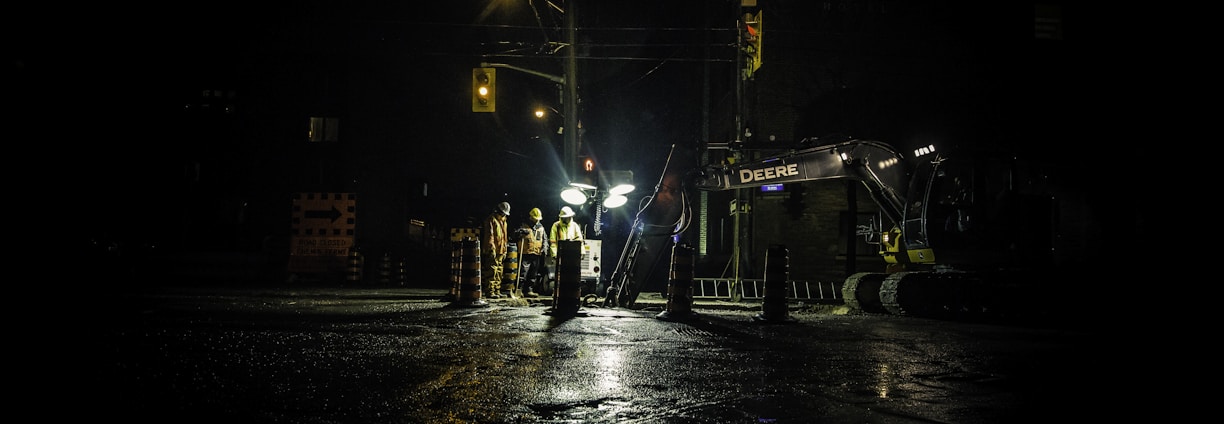 three people standing near utility post with lights turned on during nighttime