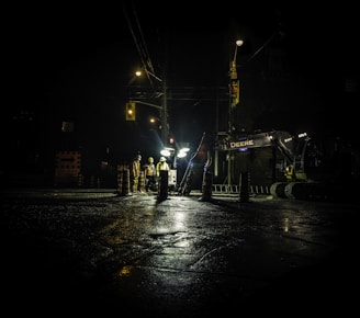 three people standing near utility post with lights turned on during nighttime