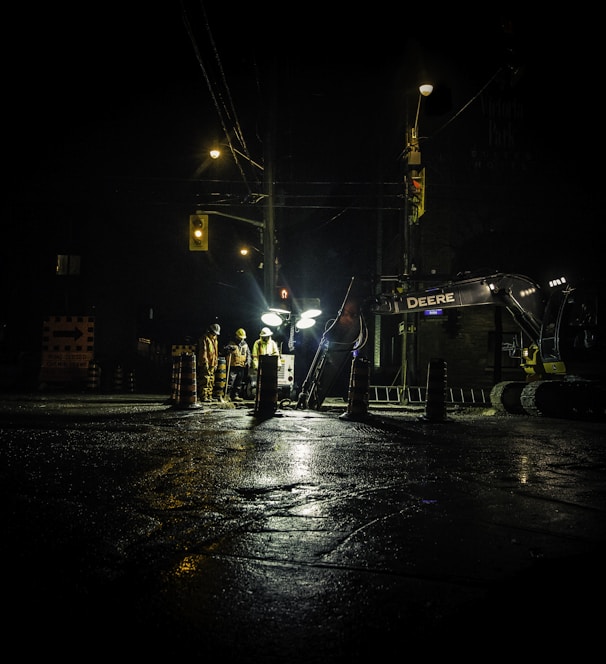 three people standing near utility post with lights turned on during nighttime