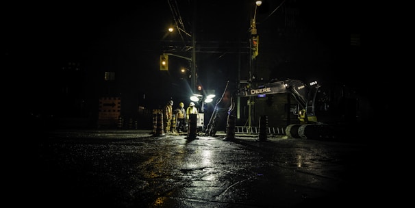 three people standing near utility post with lights turned on during nighttime