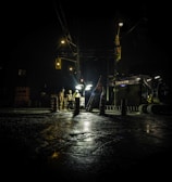 three people standing near utility post with lights turned on during nighttime
