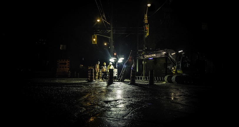three people standing near utility post with lights turned on during nighttime