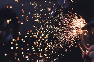 Dynamic shot of gas shielded welding sparks flying against a dark background with golden glow accents.