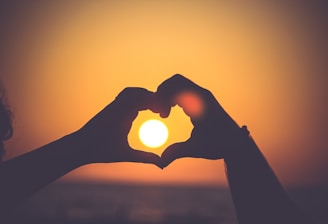 silhouette of person's hands forming heart