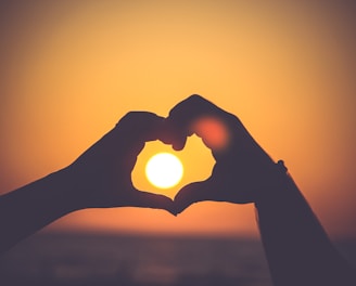 silhouette of person's hands forming heart