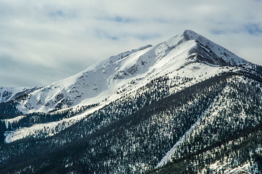 Photographie aérienne d’une chaîne de montagnes recouverte de neige sous un ciel nuageux