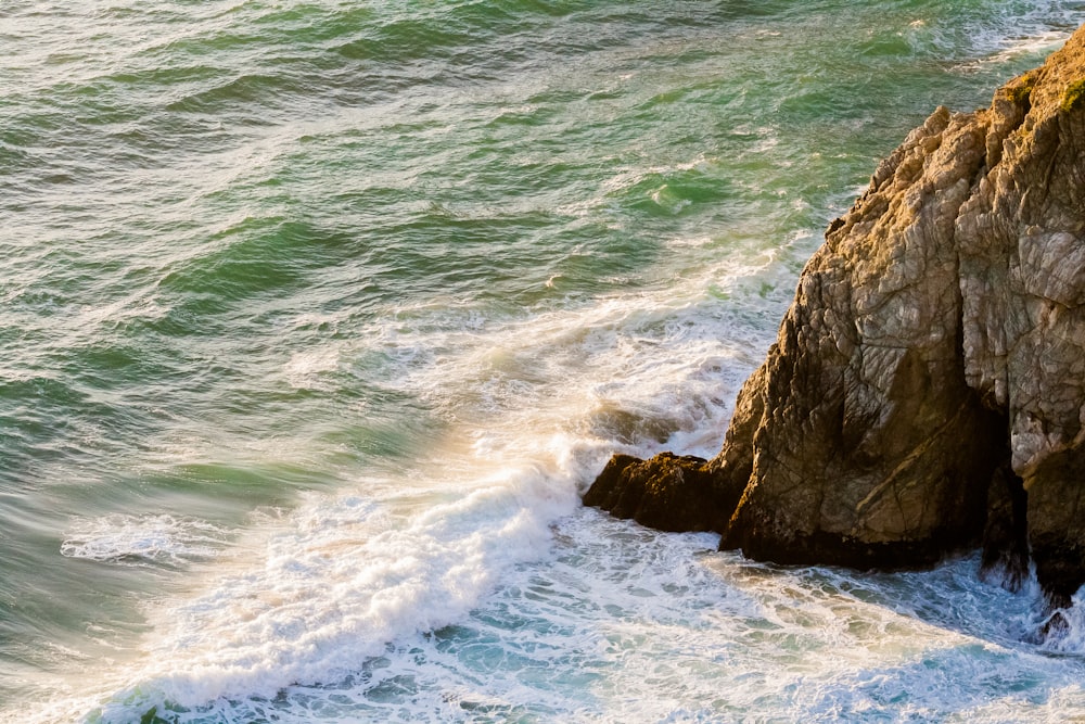 landscape photography of body of water splashing on brown mountain