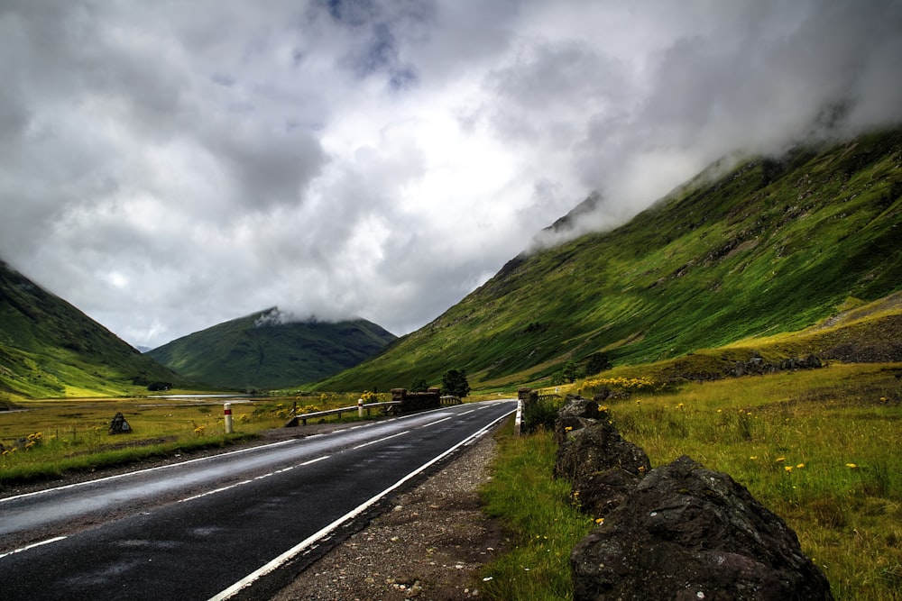 narrow road near grass and mountain