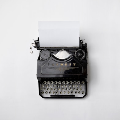 A sleek black-and-white photo of a vintage typewriter with a single sheet of paper halfway typed.