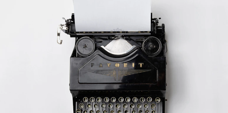 A minimalist black and white photo of a vintage typewriter on a gray desk.