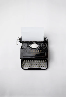 A minimalist black and white photo of a vintage typewriter on a gray desk.