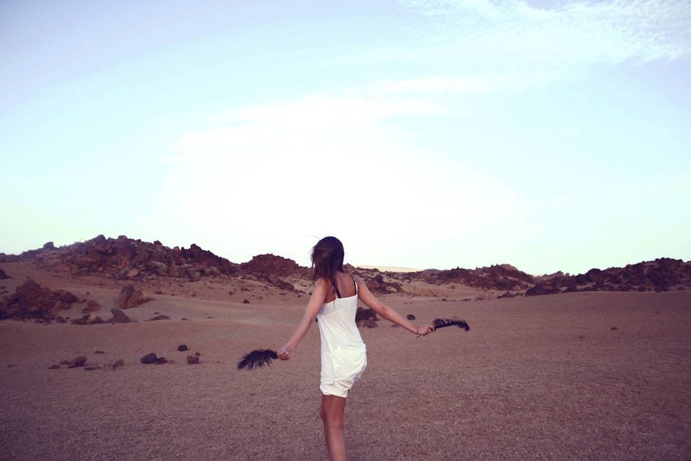 woman in white dress holding black feathers