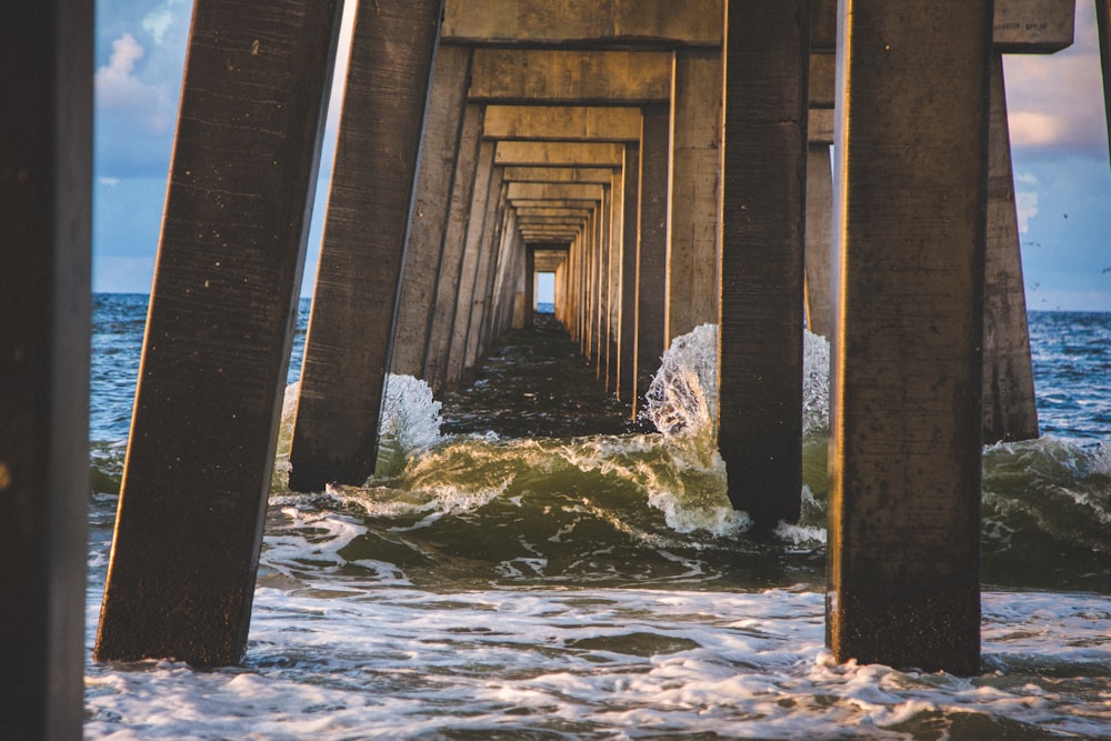 sea waves under brown concrete dock at daytime