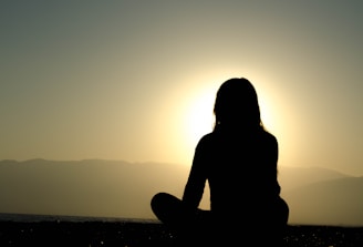 A serene scene of a person meditating at sunrise with soft light and gentle blues.