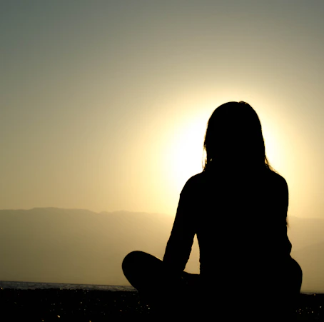 A serene scene of a person meditating outdoors at sunrise, symbolizing inner peace and self-discovery.