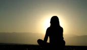 A tranquil outdoor setting with a person meditating at sunrise, embodying devotion.