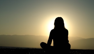 A serene yoga scene with a person meditating at sunrise.