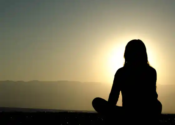 Silhouette in serene meditation pose against warm evening sunset