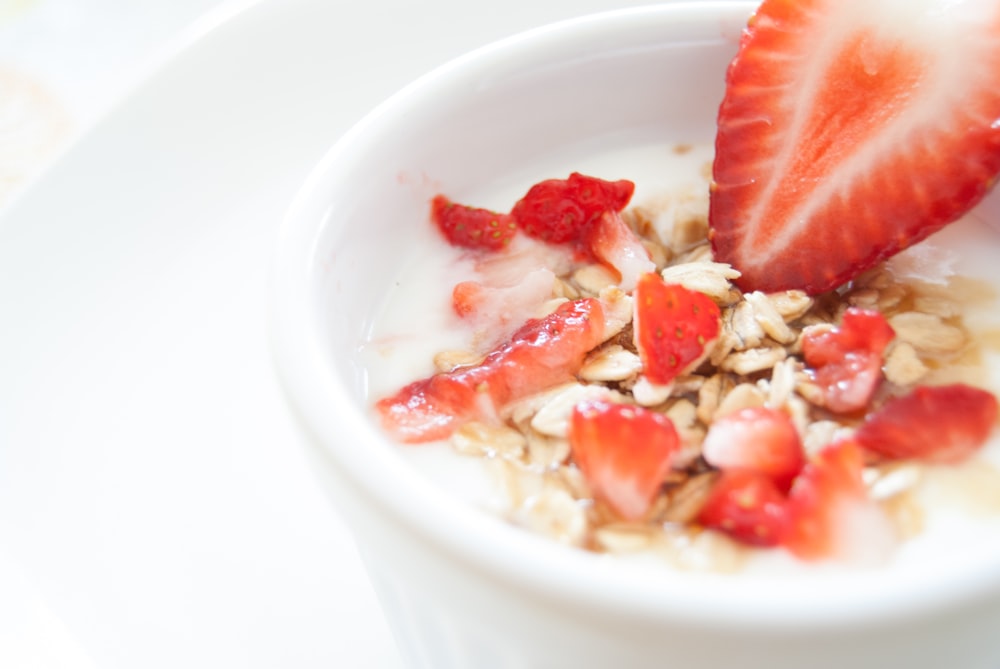 A cup of yogurt with granola and fresh strawberries