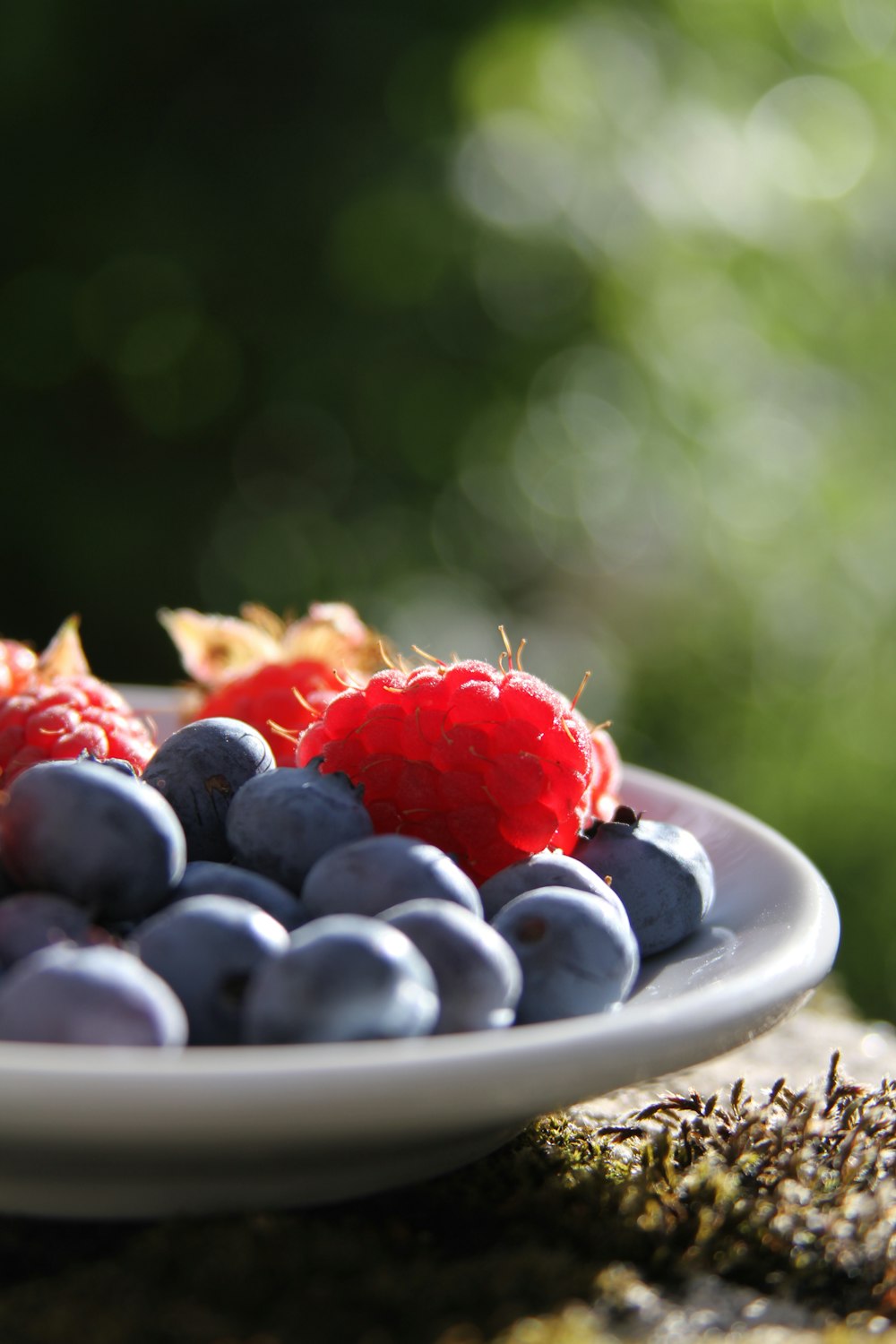 selective focus of blueberries and raspberries on bowl