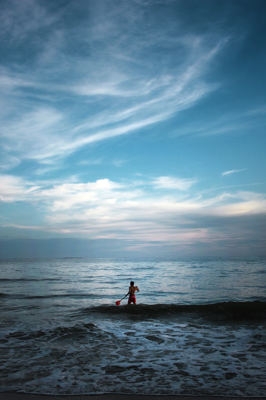 man standing on body of water holding paddle man standing on body of water holding paddle