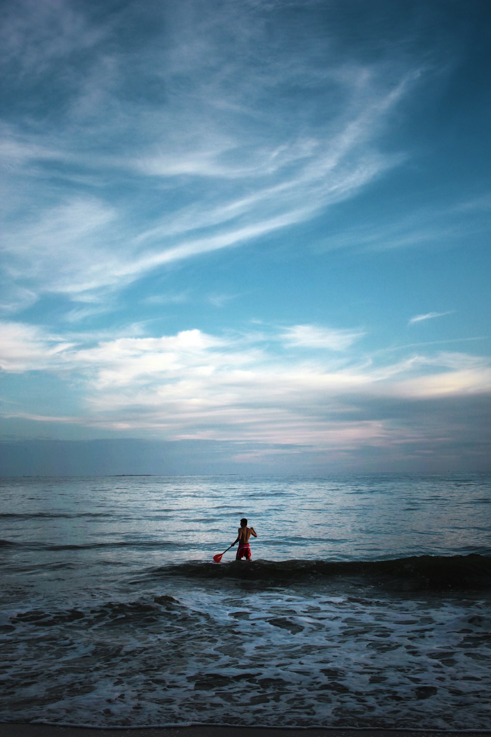 man standing on body of water holding paddle