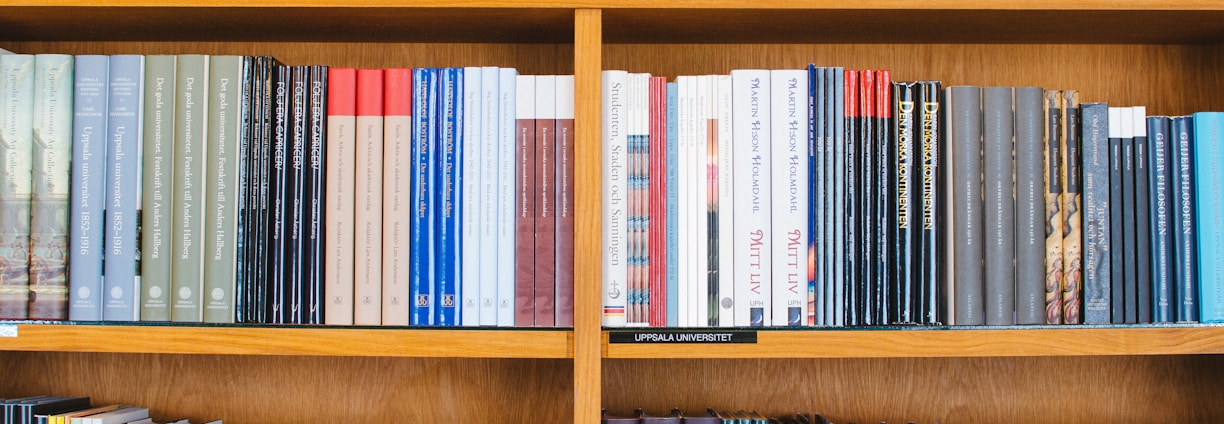 A bookshelf filled with a variety of academic and professional books, arranged neatly in rows. The spines display titles in different languages and cover various topics. Some books are thicker, while others are thinner, showing diversity in publishing styles.