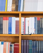 A bookshelf filled with a variety of academic and professional books, arranged neatly in rows. The spines display titles in different languages and cover various topics. Some books are thicker, while others are thinner, showing diversity in publishing styles.