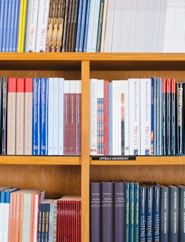 A bookshelf filled with a variety of academic and professional books, arranged neatly in rows. The spines display titles in different languages and cover various topics. Some books are thicker, while others are thinner, showing diversity in publishing styles.