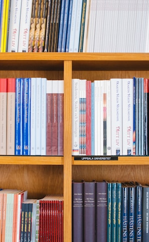 A bookshelf filled with a variety of academic and professional books, arranged neatly in rows. The spines display titles in different languages and cover various topics. Some books are thicker, while others are thinner, showing diversity in publishing styles.