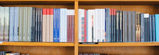 A bookshelf filled with a variety of academic and professional books, arranged neatly in rows. The spines display titles in different languages and cover various topics. Some books are thicker, while others are thinner, showing diversity in publishing styles.