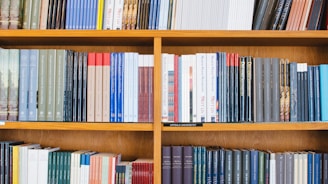 A bookshelf filled with a variety of academic and professional books, arranged neatly in rows. The spines display titles in different languages and cover various topics. Some books are thicker, while others are thinner, showing diversity in publishing styles.