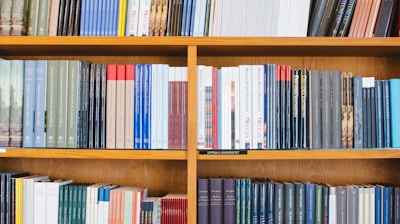 A bookshelf filled with a variety of academic and professional books, arranged neatly in rows. The spines display titles in different languages and cover various topics. Some books are thicker, while others are thinner, showing diversity in publishing styles.
