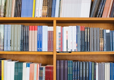 A bookshelf filled with a variety of academic and professional books, arranged neatly in rows. The spines display titles in different languages and cover various topics. Some books are thicker, while others are thinner, showing diversity in publishing styles.