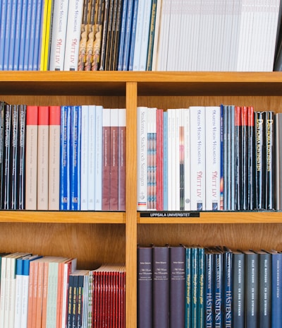 A bookshelf filled with a variety of academic and professional books, arranged neatly in rows. The spines display titles in different languages and cover various topics. Some books are thicker, while others are thinner, showing diversity in publishing styles.