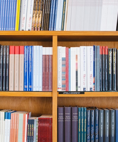 A bookshelf filled with a variety of academic and professional books, arranged neatly in rows. The spines display titles in different languages and cover various topics. Some books are thicker, while others are thinner, showing diversity in publishing styles.