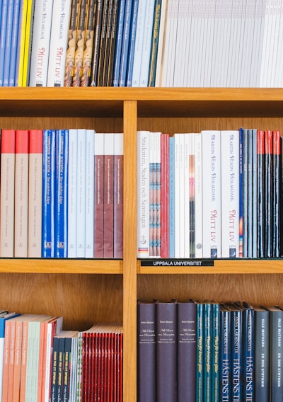 A bookshelf filled with a variety of academic and professional books, arranged neatly in rows. The spines display titles in different languages and cover various topics. Some books are thicker, while others are thinner, showing diversity in publishing styles.