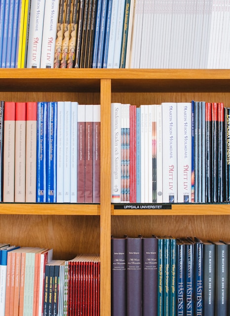 A bookshelf filled with a variety of academic and professional books, arranged neatly in rows. The spines display titles in different languages and cover various topics. Some books are thicker, while others are thinner, showing diversity in publishing styles.