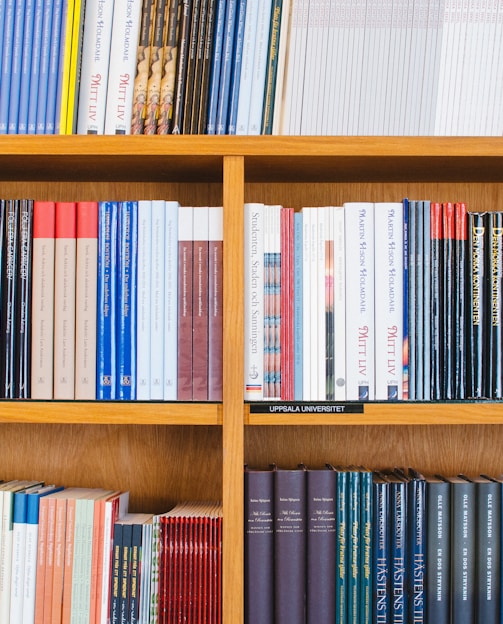 A bookshelf filled with a variety of academic and professional books, arranged neatly in rows. The spines display titles in different languages and cover various topics. Some books are thicker, while others are thinner, showing diversity in publishing styles.