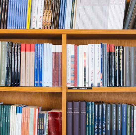 A bookshelf filled with a variety of academic and professional books, arranged neatly in rows. The spines display titles in different languages and cover various topics. Some books are thicker, while others are thinner, showing diversity in publishing styles.