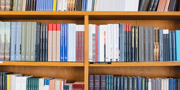 A bookshelf filled with a variety of academic and professional books, arranged neatly in rows. The spines display titles in different languages and cover various topics. Some books are thicker, while others are thinner, showing diversity in publishing styles.