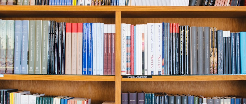A bookshelf filled with a variety of academic and professional books, arranged neatly in rows. The spines display titles in different languages and cover various topics. Some books are thicker, while others are thinner, showing diversity in publishing styles.