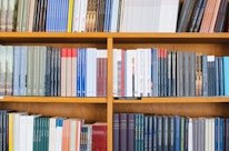 A bookshelf filled with a variety of academic and professional books, arranged neatly in rows. The spines display titles in different languages and cover various topics. Some books are thicker, while others are thinner, showing diversity in publishing styles.