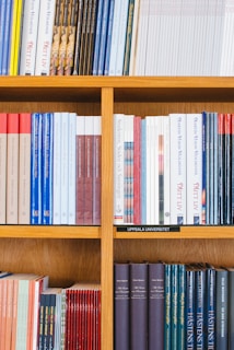 A bookshelf filled with a variety of academic and professional books, arranged neatly in rows. The spines display titles in different languages and cover various topics. Some books are thicker, while others are thinner, showing diversity in publishing styles.