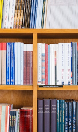 A bookshelf filled with a variety of academic and professional books, arranged neatly in rows. The spines display titles in different languages and cover various topics. Some books are thicker, while others are thinner, showing diversity in publishing styles.