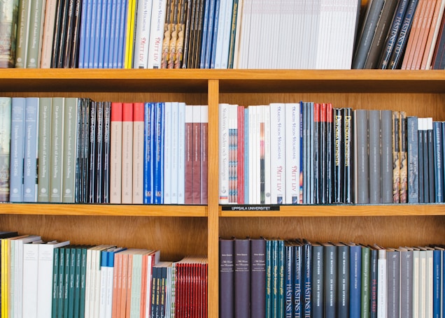 A bookshelf filled with a variety of academic and professional books, arranged neatly in rows. The spines display titles in different languages and cover various topics. Some books are thicker, while others are thinner, showing diversity in publishing styles.