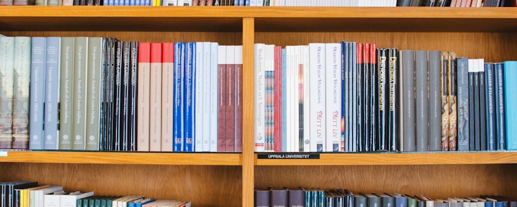 A bookshelf filled with a variety of academic and professional books, arranged neatly in rows. The spines display titles in different languages and cover various topics. Some books are thicker, while others are thinner, showing diversity in publishing styles.